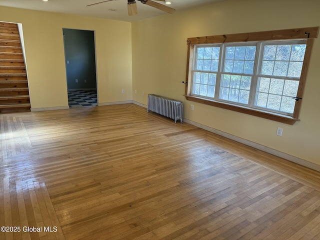 unfurnished room with baseboards, radiator heating unit, a ceiling fan, and wood-type flooring