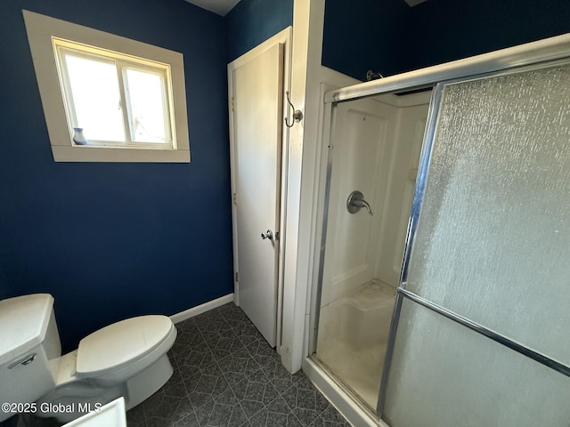 bathroom with baseboards, toilet, and a stall shower