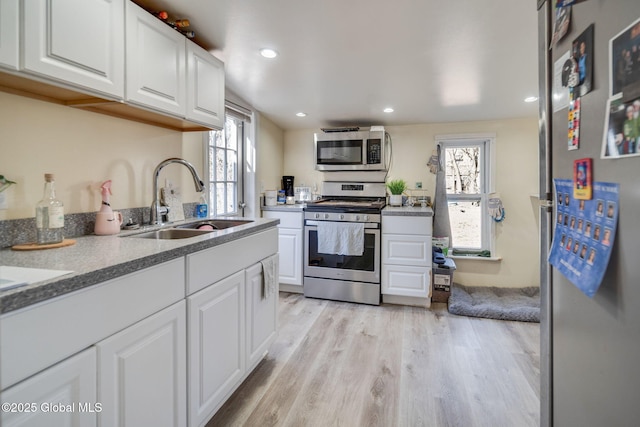 kitchen featuring plenty of natural light, appliances with stainless steel finishes, white cabinetry, and a sink