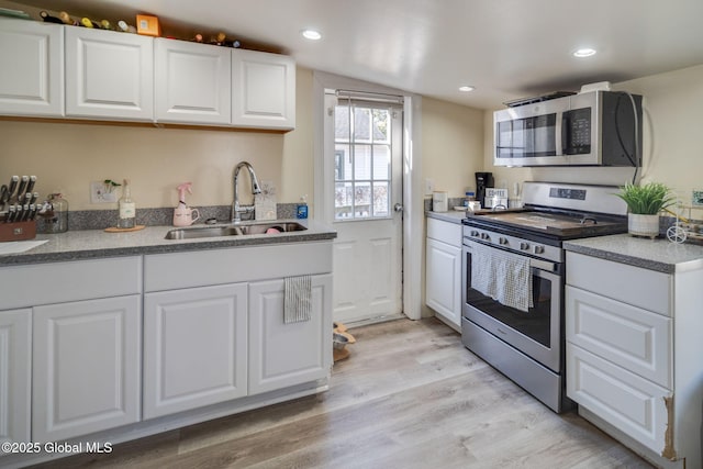 kitchen featuring light wood-type flooring, a sink, recessed lighting, appliances with stainless steel finishes, and white cabinets