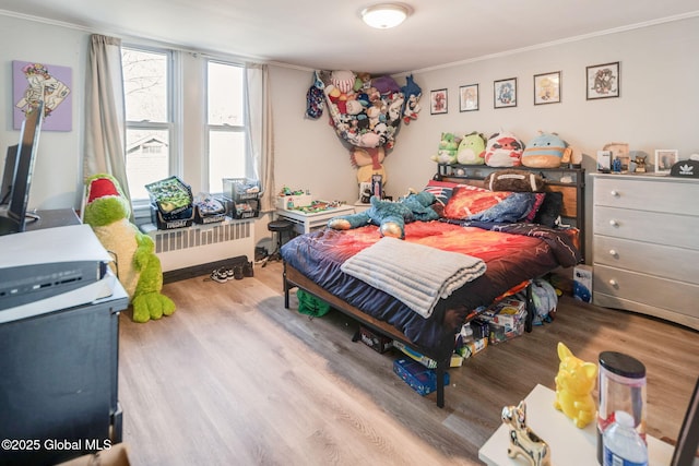 bedroom featuring wood finished floors, radiator heating unit, and ornamental molding