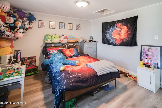 bedroom with ornamental molding and wood finished floors