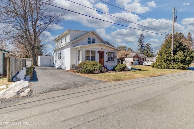 bungalow-style house featuring an outdoor structure, fence, a front lawn, and driveway