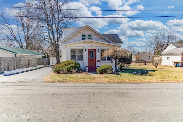 view of front facade with brick siding, a front yard, and fence