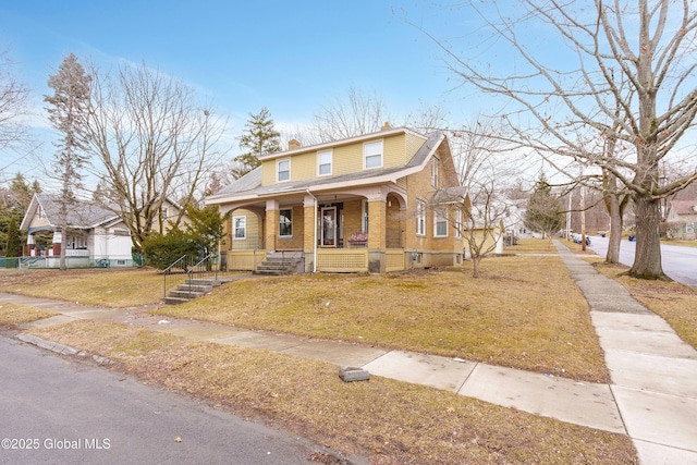 view of front of property with a front lawn, covered porch, brick siding, and a chimney