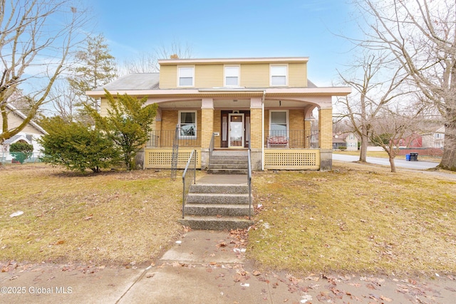 view of front of property with brick siding, a porch, and a front lawn