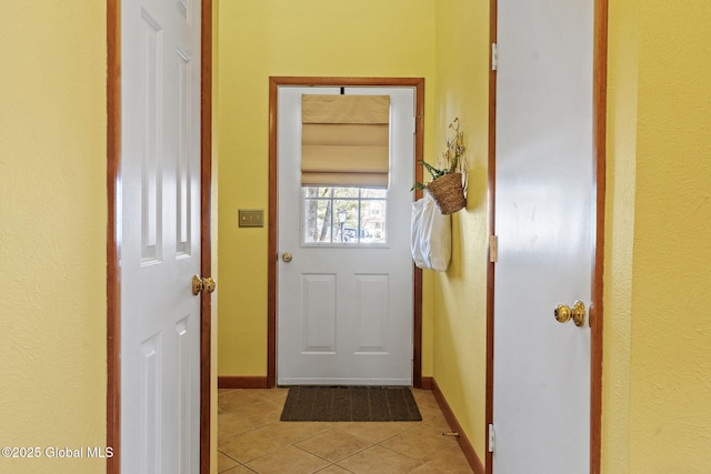 doorway featuring light tile patterned floors and baseboards