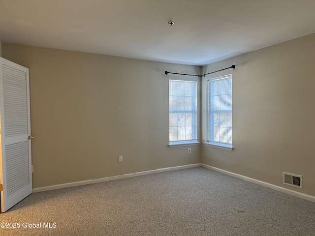 empty room with visible vents, baseboards, and light colored carpet