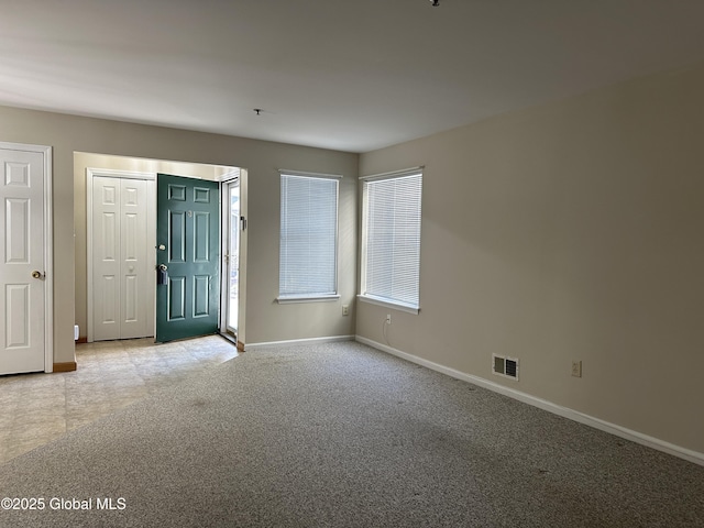 foyer with carpet flooring, baseboards, and visible vents