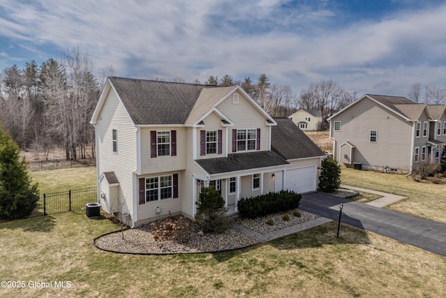 traditional-style home with a front lawn, roof with shingles, fence, and aphalt driveway