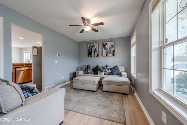 living room featuring baseboards, visible vents, ceiling fan, and light wood-type flooring