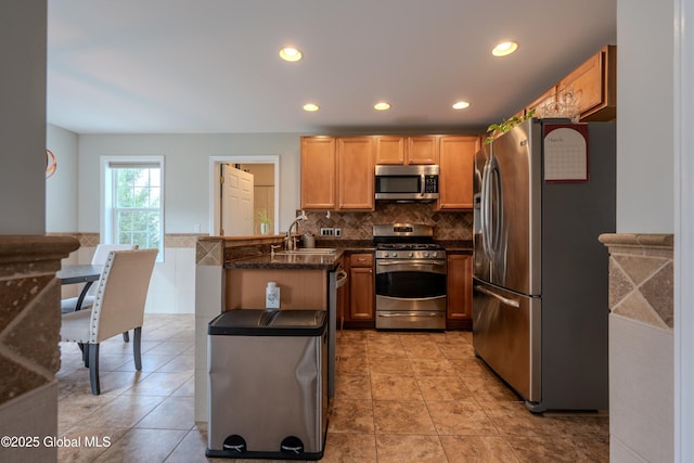 kitchen featuring a peninsula, recessed lighting, tasteful backsplash, appliances with stainless steel finishes, and a sink