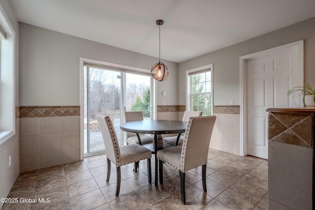dining space with tile patterned flooring, tile walls, and wainscoting