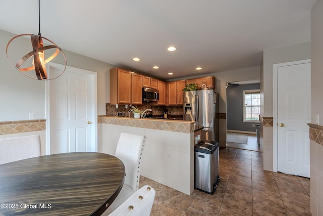 kitchen with tile patterned flooring, recessed lighting, stainless steel appliances, backsplash, and a peninsula
