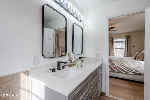 ensuite bathroom with double vanity, a sink, connected bathroom, and wood finished floors