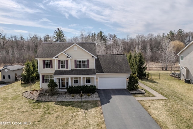 traditional home with an attached garage, driveway, fence, and a front lawn