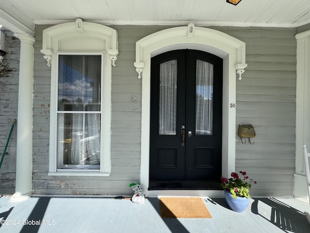 view of exterior entry featuring covered porch and french doors