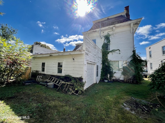 rear view of property featuring a garage, a chimney, and a yard