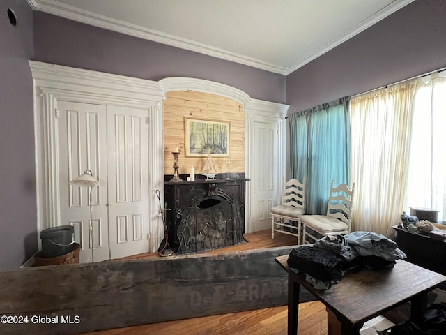 living area with a fireplace, wood finished floors, and ornamental molding