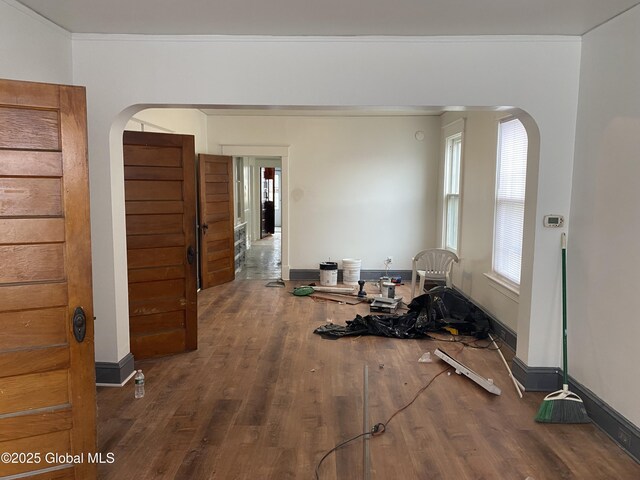 interior space featuring baseboards, arched walkways, and wood finished floors