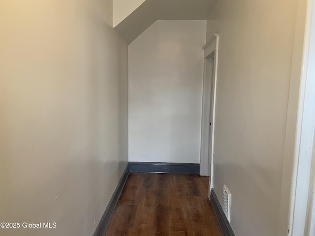 hallway with visible vents, dark wood-type flooring, and baseboards