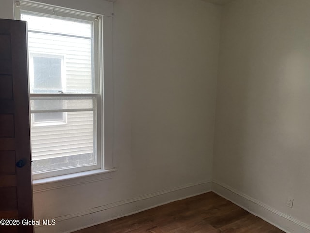 unfurnished room with dark wood-type flooring and baseboards