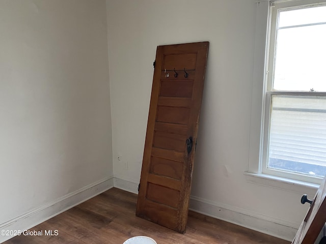 spare room featuring plenty of natural light, baseboards, and wood finished floors