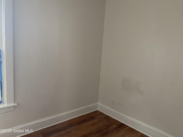 spare room with dark wood finished floors and baseboards