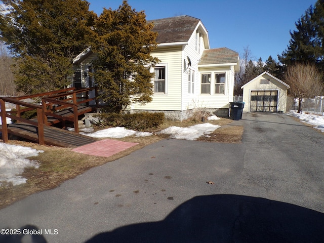 view of home's exterior featuring an outbuilding, a shingled roof, aphalt driveway, and a garage