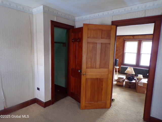 hall featuring wallpapered walls, radiator, baseboards, and carpet floors