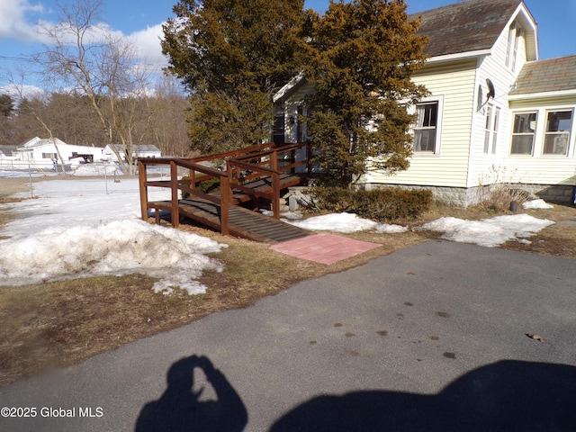 snow covered property with a shingled roof