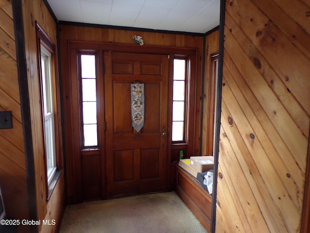 entryway featuring wooden walls and light colored carpet