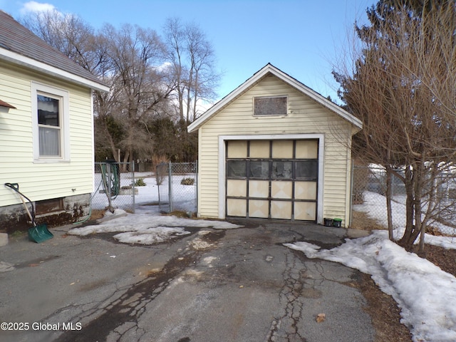 detached garage featuring aphalt driveway and fence