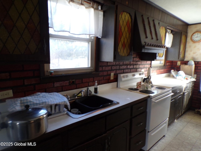 kitchen with brick wall, light countertops, electric stove, and a sink