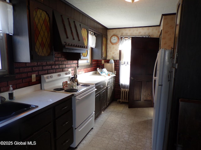 kitchen featuring white appliances, wallpapered walls, radiator heating unit, a sink, and light countertops