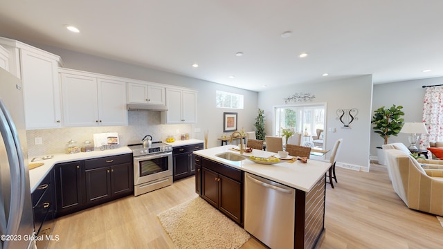 kitchen featuring white cabinets, appliances with stainless steel finishes, light wood-style flooring, and a sink