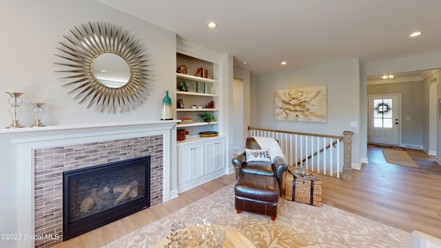 living area with wood finished floors, baseboards, a fireplace, recessed lighting, and an upstairs landing