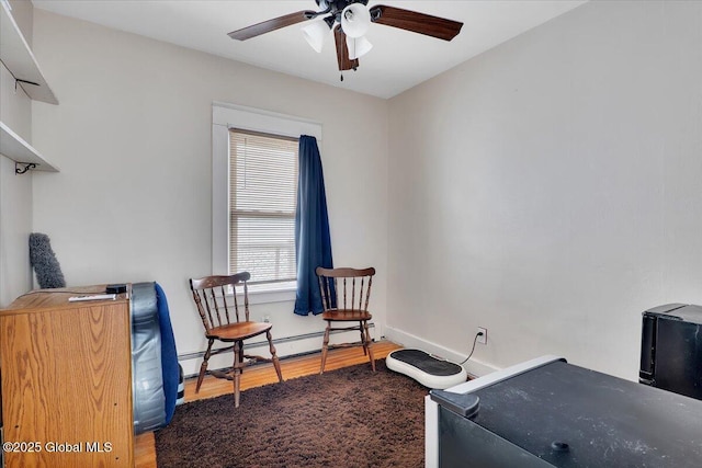 interior space with a baseboard radiator, baseboards, a ceiling fan, and wood finished floors