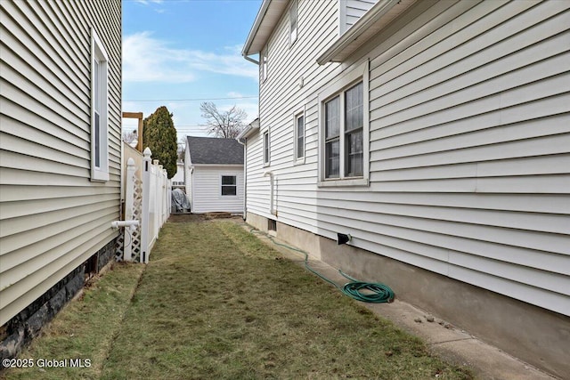 view of property exterior with a lawn and fence