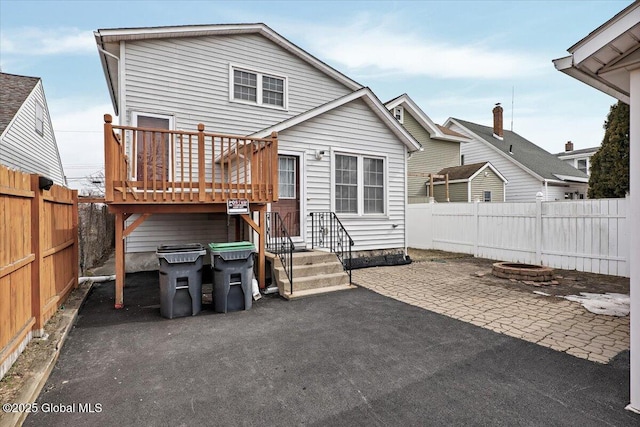 rear view of property with a deck, a patio area, and a fenced backyard