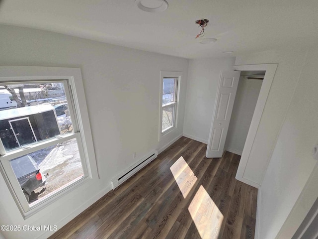 unfurnished bedroom featuring dark wood-style flooring, multiple windows, baseboards, and a baseboard radiator