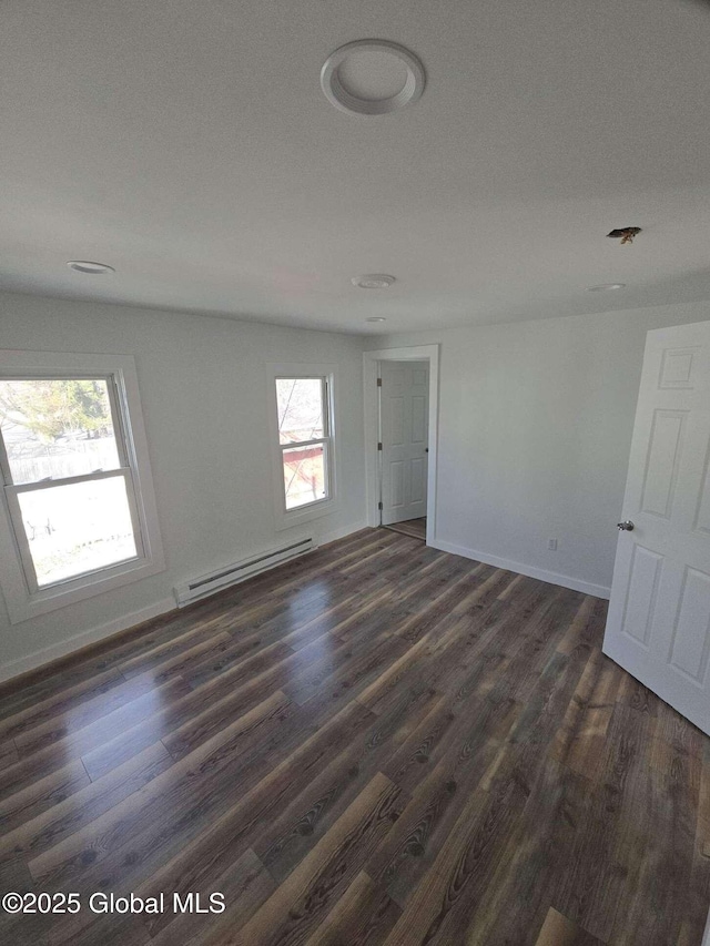 empty room with dark wood-style floors, baseboards, and a baseboard radiator