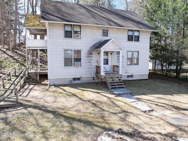 view of front of home with a balcony, cooling unit, and roof with shingles