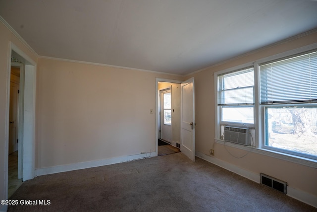 carpeted empty room with crown molding, cooling unit, baseboards, and visible vents