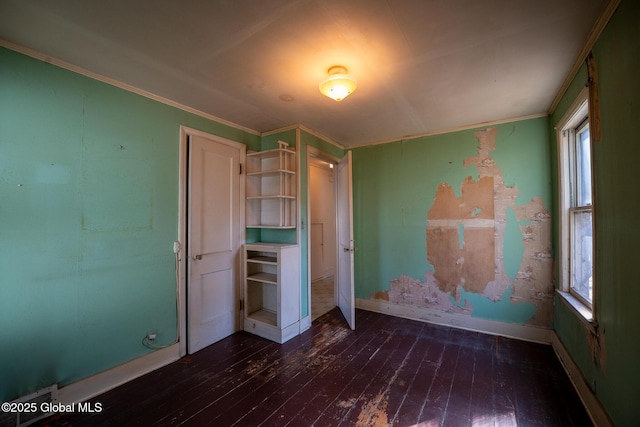 unfurnished bedroom featuring baseboards, hardwood / wood-style floors, and crown molding