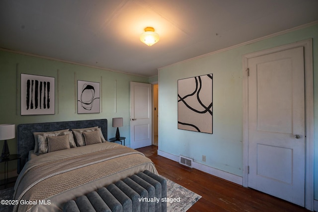 bedroom with visible vents, ornamental molding, baseboards, and wood finished floors