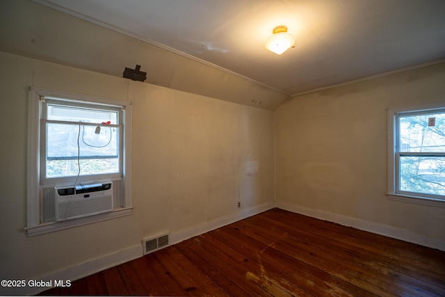 spare room with cooling unit, baseboards, visible vents, vaulted ceiling, and dark wood-type flooring