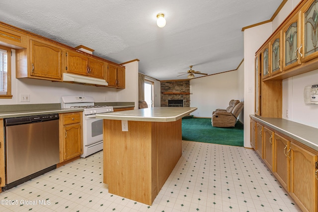 kitchen with white gas stove, under cabinet range hood, light floors, a fireplace, and stainless steel dishwasher