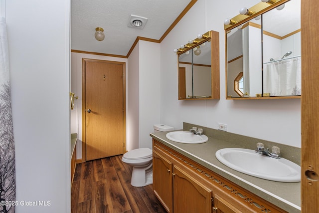 bathroom featuring crown molding, wood finished floors, visible vents, and a sink