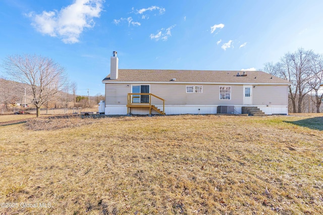 rear view of property with a lawn, central AC, and a chimney